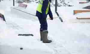 Professional snow removal worker shoveling a snowy walkway in Montgomery County